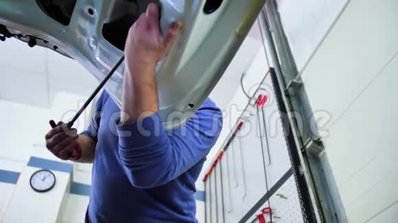 无油漆凹痕修复主人在汽车修理车间的引擎盖上对齐凹痕底部视图工具视频的预览图
