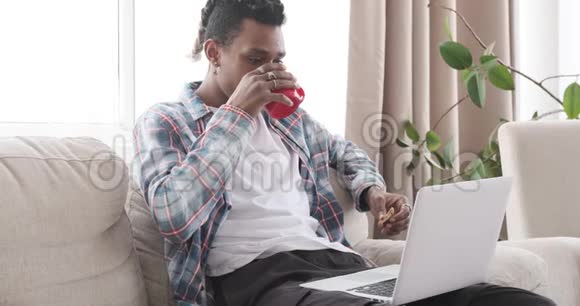 男人一边吃早餐一边看笔记本电脑上的媒体内容视频的预览图