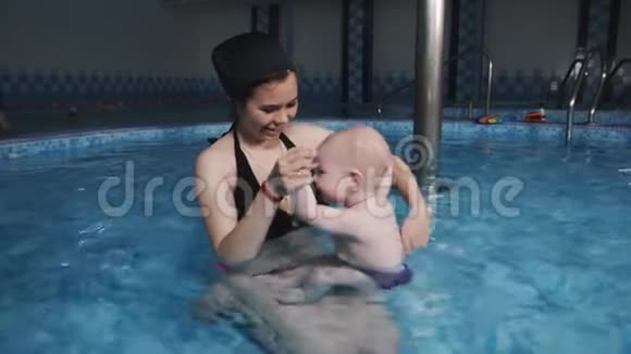一位母亲带着一个小儿子在游泳池健身中心做水上体操视频的预览图