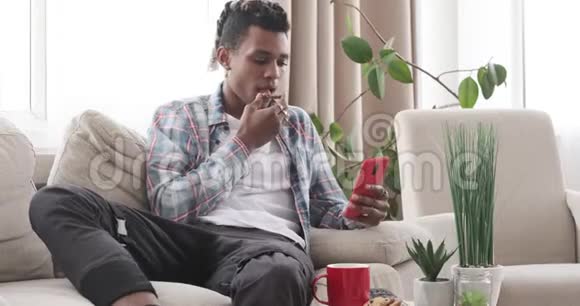 男人在沙发上用手机吃早餐视频的预览图