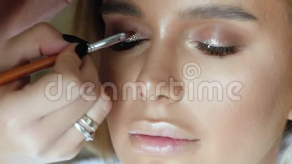 化妆师用一个年轻漂亮的女人做化妆睫毛视频的预览图