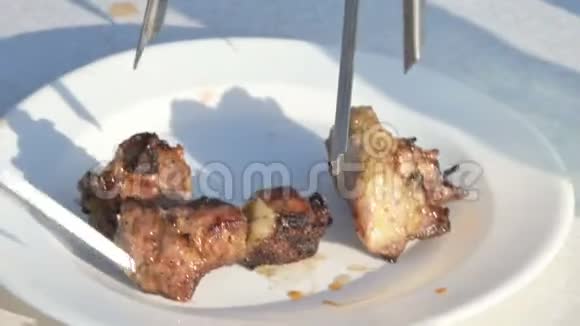 烤架上的一小块新鲜开胃的猪肉用刀子从烤架上切下来放到露天的盘子里视频的预览图