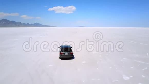 无人机跟着银色的小型货车在令人叹为观止的邦纳维尔盐湖沙漠中朝山行驶视频的预览图