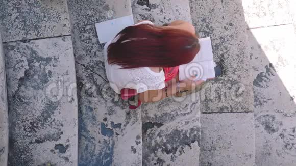 女孩在大理石楼梯上看书高角度拍摄意大利视频的预览图