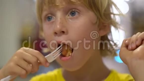 一个小男孩在街头咖啡馆吃美味的华夫饼的特写镜头街头食品概念视频的预览图