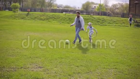 长胡子的父亲和两个女儿在体育场踢足球夏日绿草如茵视频的预览图