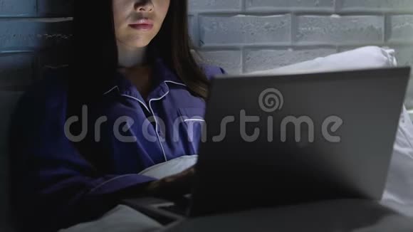 女性自由职业者深夜在床上打字远程访问工作视频的预览图
