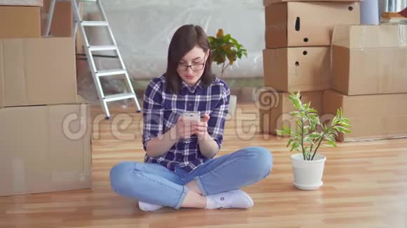 年轻女子用手机在背景盒中移动新家视频的预览图