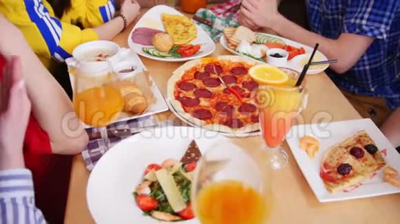 一群朋友坐在咖啡馆里满桌的食物吃匹萨意大利香肠视频的预览图