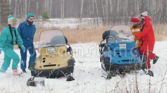 冬天一家人穿着五颜六色的夹克骑着雪地摩托谈笑风生开始骑马视频的预览图