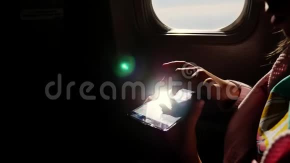 特写镜头太阳光线反射在手机上儿童手和手机面对飞机的黑暗轮廓视频的预览图