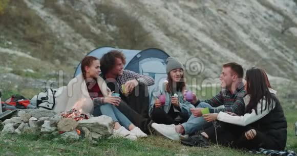 一群有魅力的青少年在山上野餐坐在篝火旁喝点酒视频的预览图