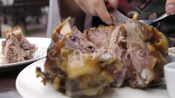 人手拿刀叉切一个猪肉指节放在盘子上附近有一杯啤酒视频的预览图