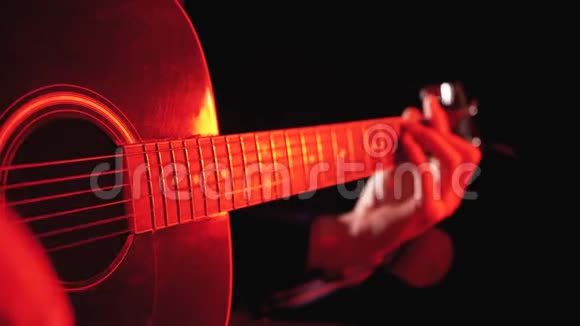 用红色背光和黑色背景演奏声学吉他视频的预览图