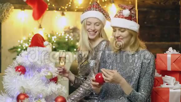新年里微笑的女孩帽子喝香槟装饰圣诞树女孩们装饰圣诞树新视频的预览图
