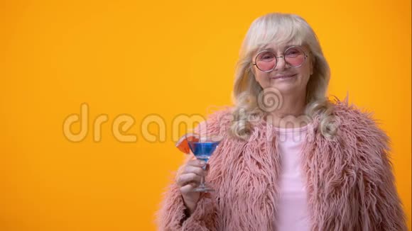 欢乐的老年妇女在镜头前用蓝色鸡尾酒做咯咯响的手势派对视频的预览图