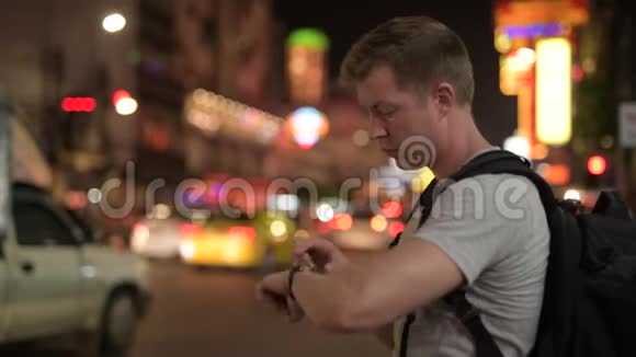 夜间在唐人街年轻的游客背包客在打电话和打出租车时等候视频的预览图