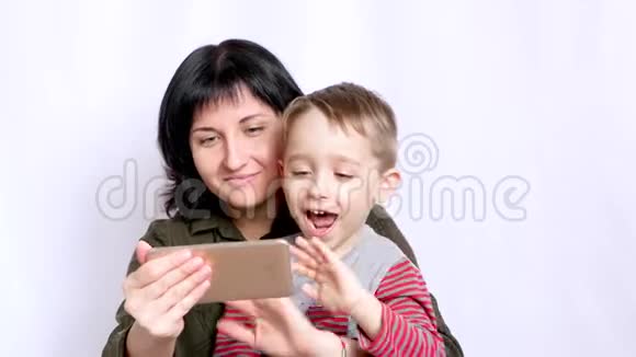一位快乐的年轻母亲和孩子正在看着智能手机的屏幕在交流时挥舞着手视频的预览图