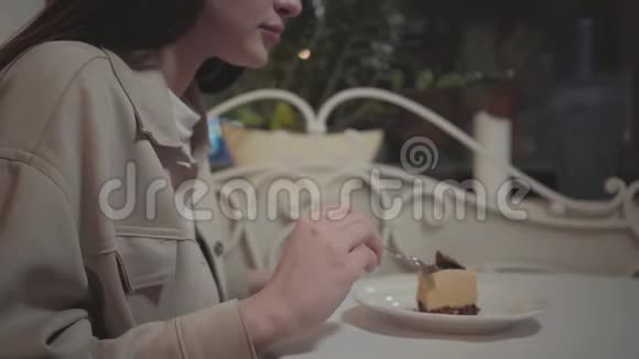 年轻的女人在咖啡馆里吃着一小块美味的蛋糕那个女孩在现代享受甜点视频的预览图