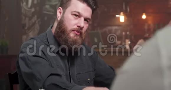 一个大胡子男人在酒吧和一个朋友喝着威士忌视频的预览图