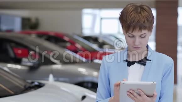 在车展上一位穿着正式服装的自信漂亮的女士站在模糊的汽车前视频的预览图