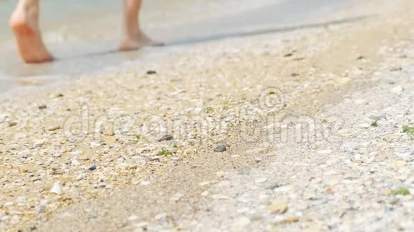 光着脚走在阳光明媚的海滩上的人视频的预览图