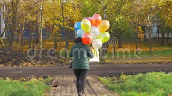 在美丽的秋日一个带着气球走着的女人的慢动作视频的预览图