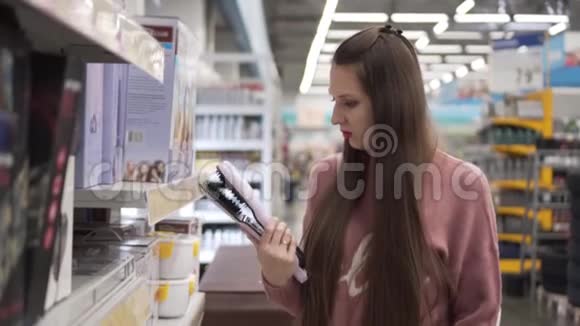 年轻女子在超市里选择了理发器视频的预览图