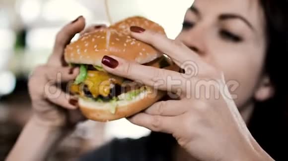 一个年轻的女孩有一个很大的开胃芝士汉堡把它握在手里视频的预览图