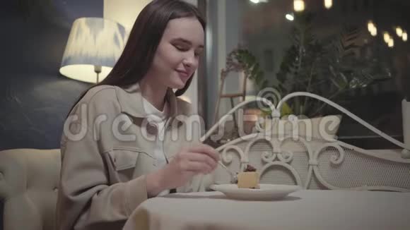 一幅年轻女人在咖啡馆里吃小块美味蛋糕的肖像那个女孩在她的甜点中享受着视频的预览图
