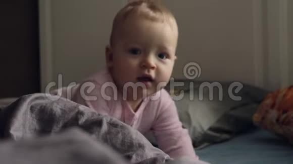 一个穿着粉色浪漫套装的女婴躺在凌乱的床上视频的预览图