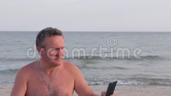 男人在海浪的背景下在海滩上自拍视频的预览图
