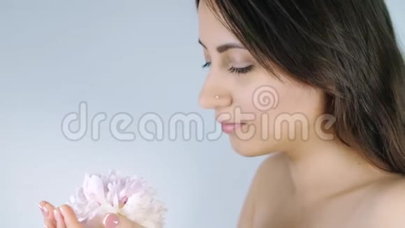 女人闻着白色背景上的花视频的预览图
