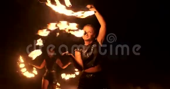 三个拿着燃烧的铁箍的女人在一个黑暗的机库里用火把在皮衣上跳舞表演马戏团的火视频的预览图