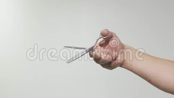 一位男士理发师手持剪刀的特写视频的预览图