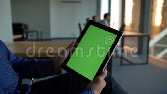 西班牙商人手里拿着一台绿色屏幕的黑色平板电脑视频的预览图