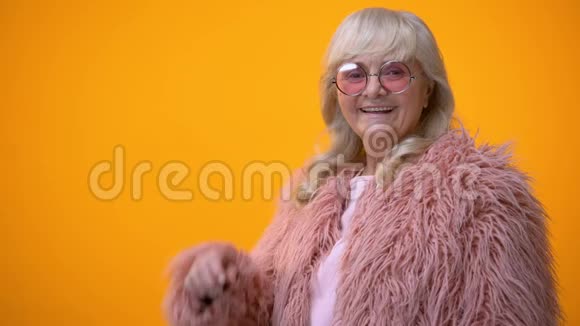 带着粉色外套和圆墨镜的老太太正笑着眨眨眼调情视频的预览图
