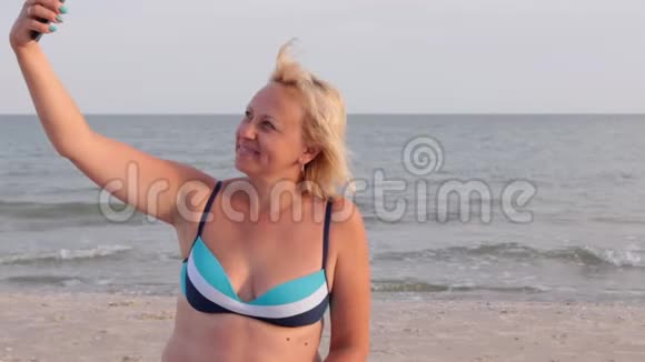 女人在海浪的背景下在海滩上自拍视频的预览图