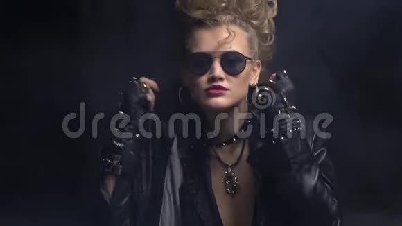 漂亮的摇滚女孩戴着太阳镜调整着皮夹克上的衣领动作缓慢视频的预览图