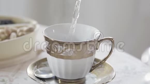 用热茶把白色和金色的瓷杯贴在桌子上库存录像热水是视频的预览图