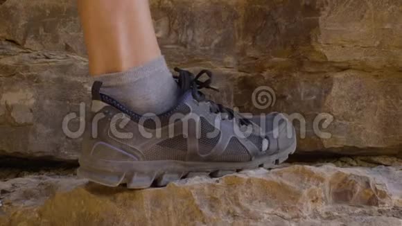 在旅行时穿着徒步旅行靴爬到岩石山穿着登山鞋的男性徒步到悬崖视频的预览图