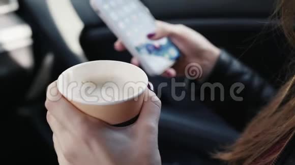 在一个坐在车里的女人的手中合上一杯咖啡和电话侧视视频的预览图