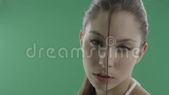 性感的年轻女人脸上沾着湿发的绿色背景视频的预览图