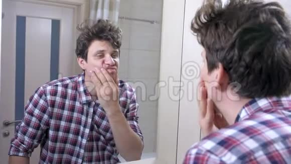 疲惫的睡醒男人在浴室里宿醉看着镜子洗脸视频的预览图