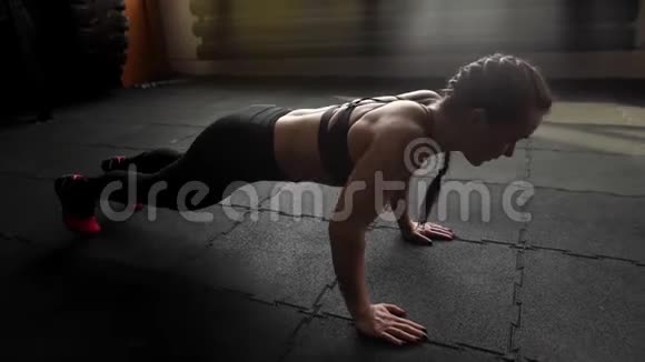 运动型美女在体育馆里慢动作地在地板上做俯卧撑视频的预览图