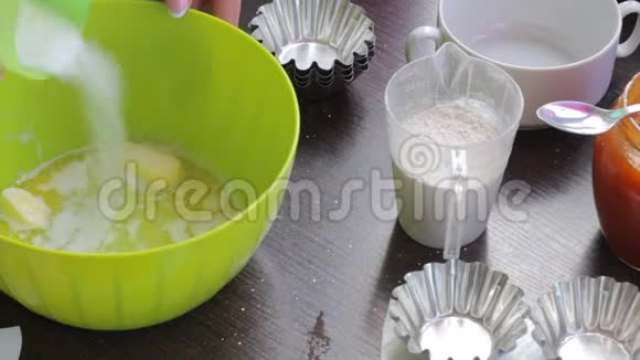 一个女人在一个融化的黄油容器里加入面粉和糖开始揉面做蛋糕视频的预览图