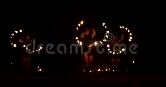三个拿着燃烧的铁箍的女人在一个黑暗的机库里用火把在皮衣上跳舞表演马戏团的火视频的预览图