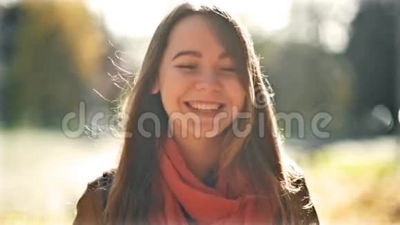 快乐的年轻美丽的女人笑着看着镜头秋天公园的背景十月初秋视频的预览图