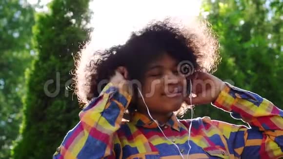 美国黑人女性快乐的肖像穿着衬衫戴着耳机的非洲发型视频的预览图