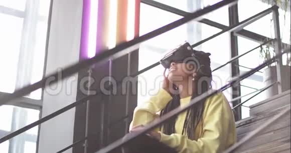 一位坐在楼梯上的现代商务中心戴着可怕眼镜的非洲女士正在探索视频的预览图
